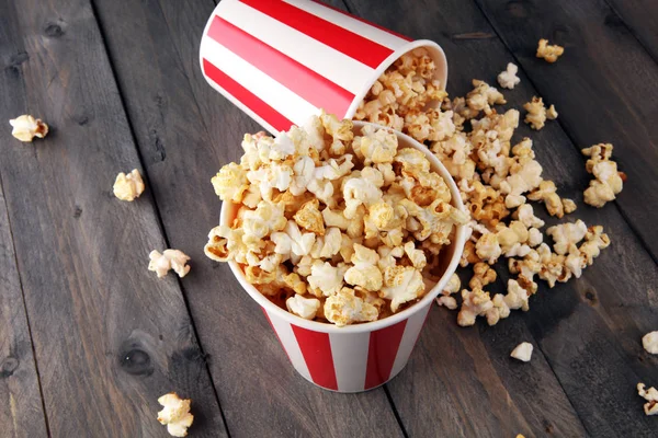 Paper cup in red and white with popcorn on wooden background. — Stock Photo, Image