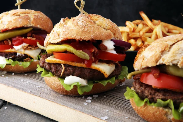Čerstvé chutné hamburgery a hranolky na dřevěném stole. — Stock fotografie