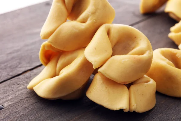 Surowy ser wypełnione makaronu tortellini na podłoże drewniane. — Zdjęcie stockowe