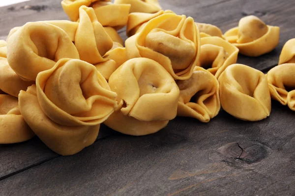 Nyers sajtot töltött tortellini tészta fából készült háttér. — Stock Fotó