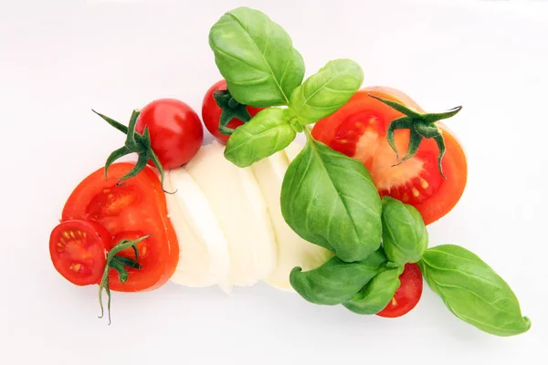 Mozzarella et tomate aux feuilles de basilic sur fond de bois blanc — Photo