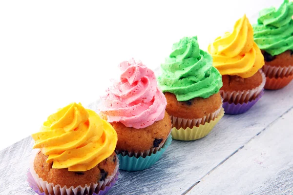 Cupcakes saborosos no fundo de madeira. Bolo de aniversário em arco-íris — Fotografia de Stock