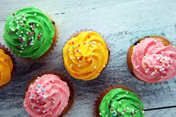 Cupcakes saborosos no fundo de madeira. Bolo de aniversário em arco-íris — Fotografia de Stock