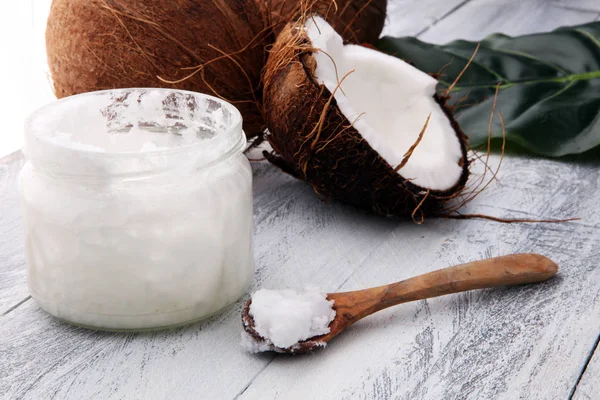 Kokosnuss und geöffnetes Glas mit frischem Kokosöl auf hölzernem Ba — Stockfoto