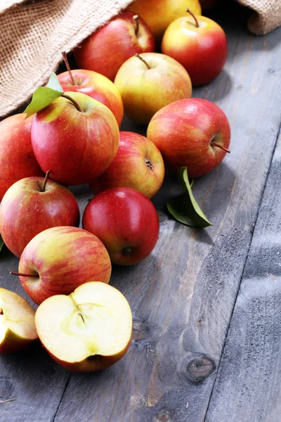 Ώριμα κόκκινα μήλα με φύλλα σε φόντο ξύλινη. — Φωτογραφία Αρχείου
