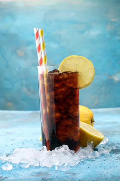Softdrank met ijsblokjes, citroen en stro in glas. — Stockfoto