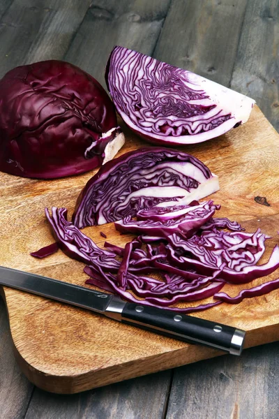 Shredded cabbage, red cabbage on wooden cutting board.