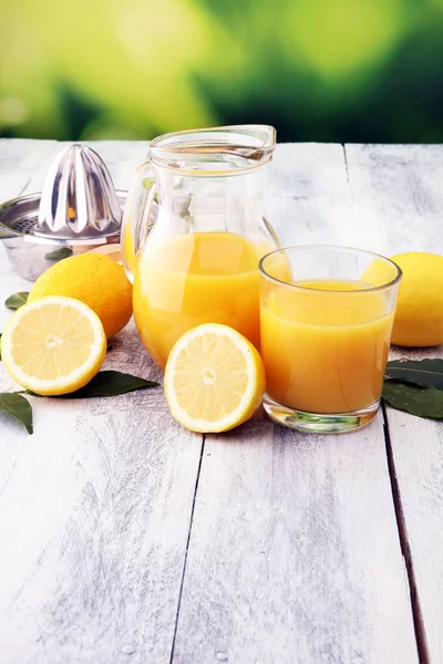 Склянка лимонного соку і скибочки апельсинових фруктів на дерев'яному фоні — стокове фото