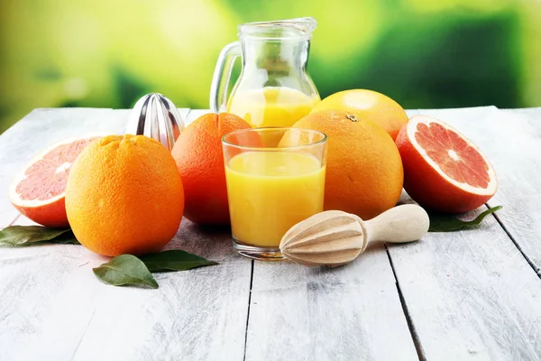 Glass of grapefruit juice and slices of orange fruit on wooden b — Stock Photo, Image