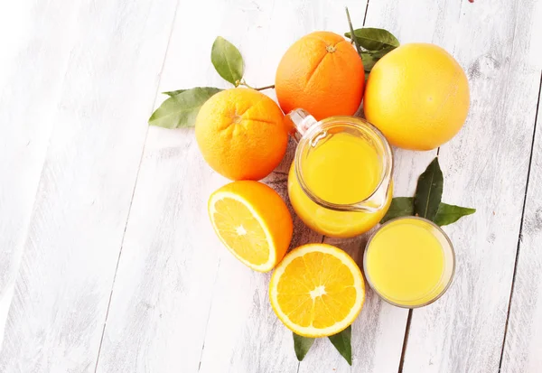 Склянка апельсинового соку і скибочки апельсинових фруктів на дерев'яному фоні — стокове фото