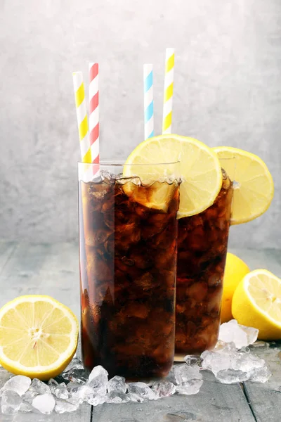 Nealkoholický nápoj s kostkami ledu, citrónem a slámou ve skle. — Stock fotografie