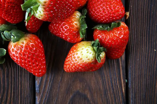 Fresh strawberries on brown wooden background. A group of strawb — Stock Photo, Image