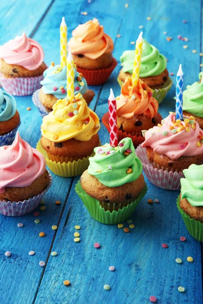 Cupcakes saborosos no fundo de madeira. Bolo de aniversário em arco-íris — Fotografia de Stock