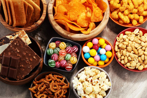 Соленые закуски. Крендельки, чипсы, крекеры в деревянных мисках
.