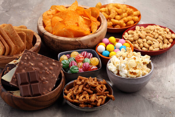 Соленые закуски. Крендельки, чипсы, крекеры в деревянных мисках
.