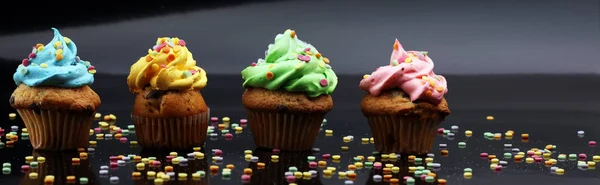 Cupcakes saborosos no fundo escuro. Bolo de aniversário em arco-íris c — Fotografia de Stock