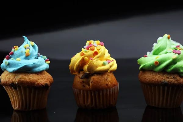 Cupcakes saborosos no fundo escuro. Bolo de aniversário em arco-íris c — Fotografia de Stock