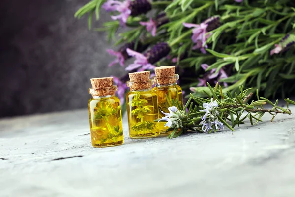 Lavendelöl in einer Glasflasche vor einem Hintergrund frischer Blumen. — Stockfoto