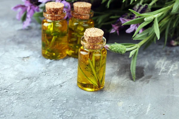 Lavendelöl in einer Glasflasche vor einem Hintergrund frischer Blumen. — Stockfoto