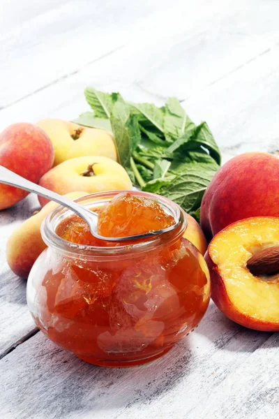 Peach vanilla jam with fresh peaches on table.