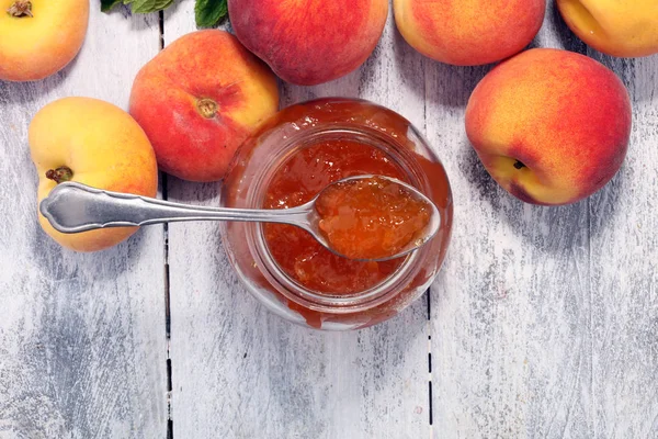 Peach vanilla jam with fresh peaches on table.