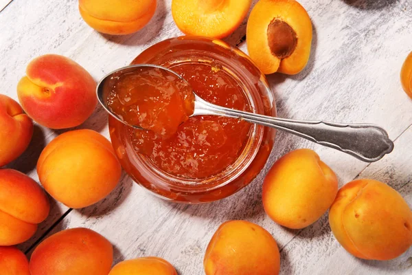 apricot jam and a bunch of fresh apricots on wooden table.