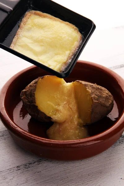 Raclette sýr tavení na bramborách podávané v jednotlivých pánvích. — Stock fotografie