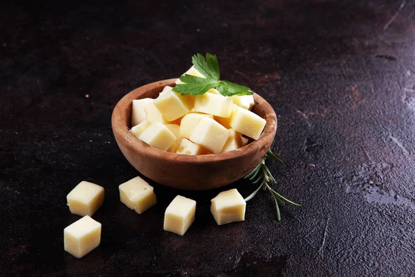 Cubos de queso en cuenco de madera con perejil. trozos de queso en la mesa — Foto de Stock