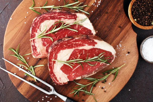Carne fresca crua Bife de Ribeye, tempero e garfo de carne em rústico b — Fotografia de Stock