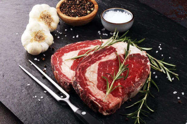 Obearbetat färskt kött Ribeye Biff, krydda och köttgaffel på rustik b — Stockfoto