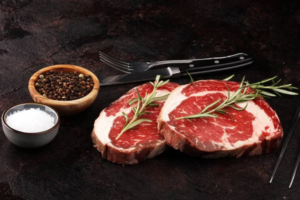 Carne fresca cruda Ribeye Filete, condimento y tenedor de carne en rústico b — Foto de Stock