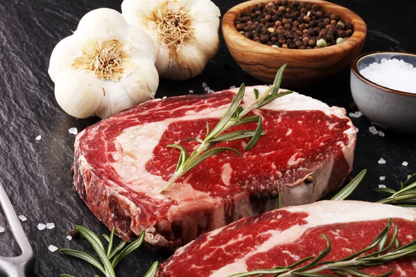 Carne fresca cruda Ribeye Filete, condimento y tenedor de carne en rústico b — Foto de Stock