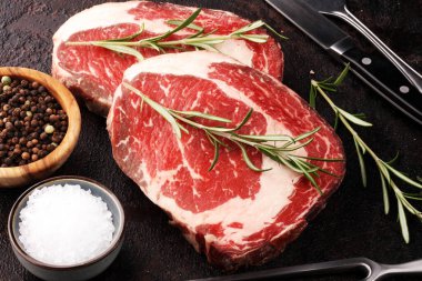 Çiğ et, pirzola, baharat ve et çatalı.