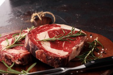 Çiğ et, pirzola, baharat ve et çatalı.