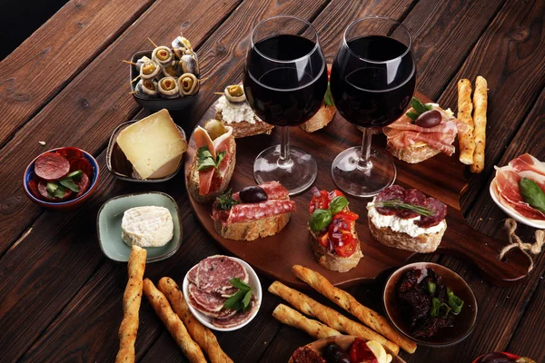 Appetizers table with italian antipasti snacks and wine in glass