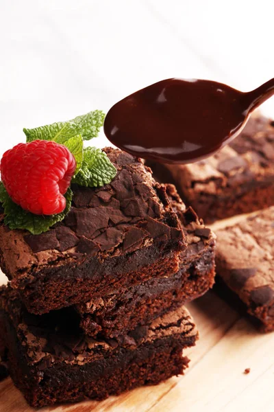 chocolate brownie cake dessert with raspberries and spices on a wooden background.