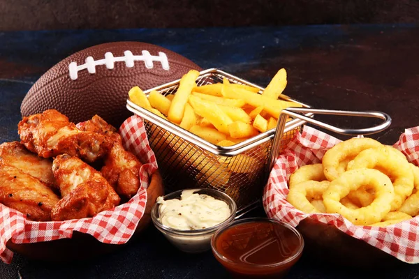 chicken wings, fries and onion rings for football on a table. Gr