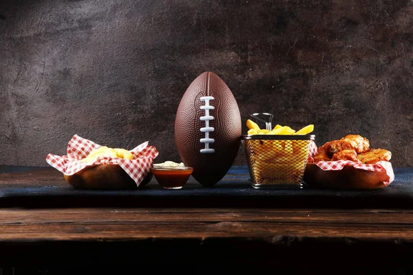tavuk kanatları, patates kızartması ve bir masada futbol için soğan halkaları. Gr