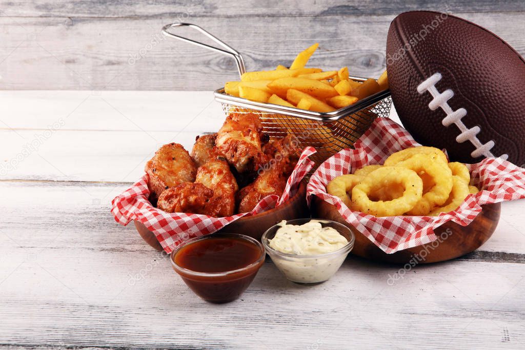 chicken wings, fries and onion rings for football on a table. Gr