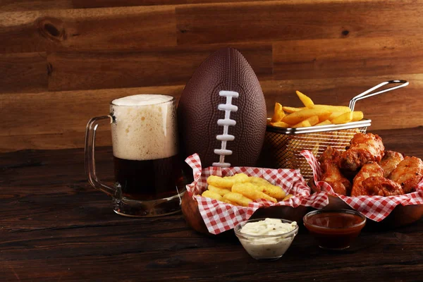 Ali di pollo, patatine fritte e anelli di cipolla per calcio su un tavolo. Gr. — Foto Stock
