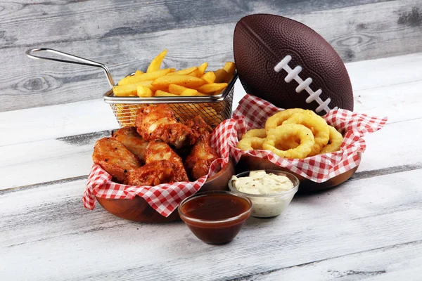 Las alas de gallina, las patatas fritas y los aros de cebolla para el fútbol sobre la mesa. Gr. — Foto de Stock