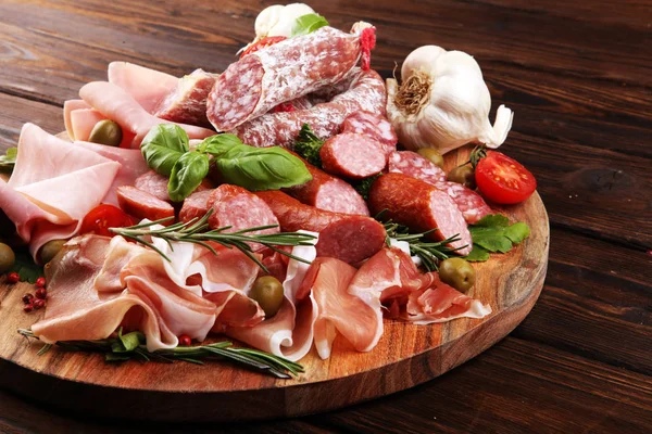 Bandeja de comida con delicioso salami, trozos de jamón crudo en rodajas —  Fotos de Stock