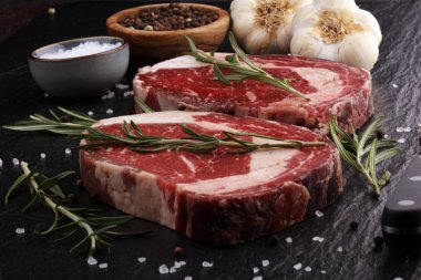 Çiğ et, pirzola, baharat ve et çatalı.
