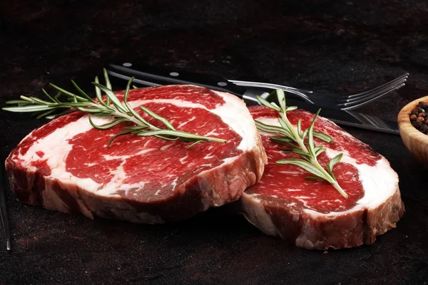 Carne fresca cruda Ribeye Filete, condimento y tenedor de carne en rústico b — Foto de Stock