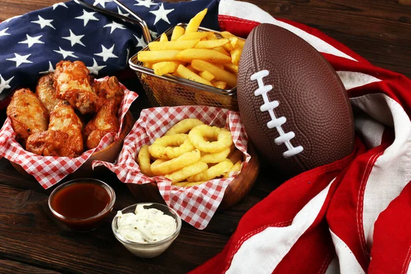 chicken wings, fries and onion rings for football on a table. Gr