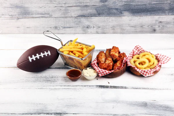 Las alas de gallina, las patatas fritas y los aros de cebolla para el fútbol sobre la mesa. Gr. — Foto de Stock