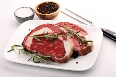 Çiğ et, pirzola, baharat ve et çatalı.