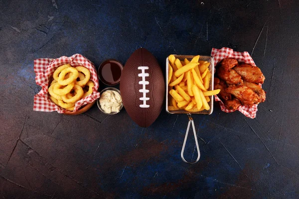 Las alas de gallina, las patatas fritas y los aros de cebolla para el fútbol sobre la mesa. Gr. — Foto de Stock