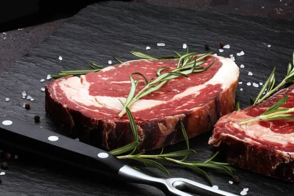 Carne fresca cruda Ribeye Filete, condimento y tenedor de carne en rústico b — Foto de Stock