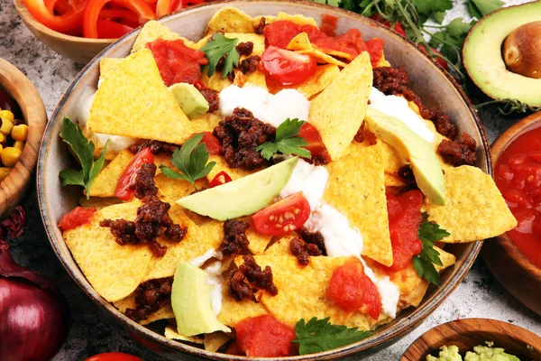 Mexican nacho chips garnished with ground beef, guacamole, melte — 스톡 사진